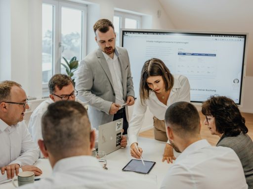 a group of people sitting around a table with laptops