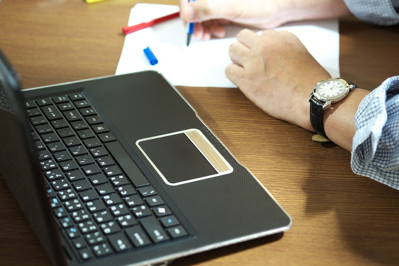 Persoon die achter een laptop studeert aan een bureau, bezig met een online cursus of opleiding