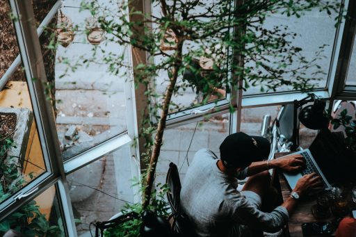 Zzp'er werkt aan laptop in een zomers café en beheert zijn financiën tijdens de rustige zomerperiode