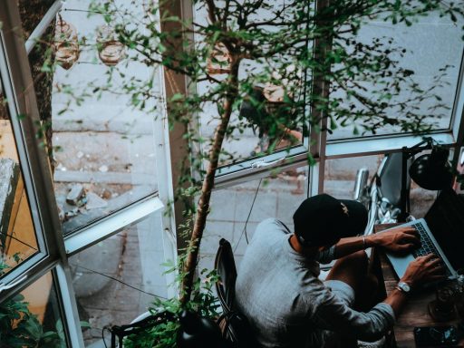 Zzp'er werkt aan laptop in een zomers café en beheert zijn financiën tijdens de rustige zomerperiode
