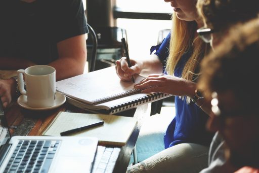 Twee ondernemers in gesprek aan een vergadertafel met documenten en een laptop