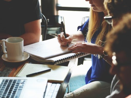 Twee ondernemers in gesprek aan een vergadertafel met documenten en een laptop