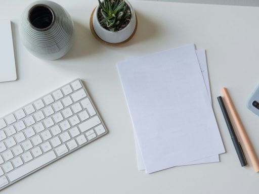 white printer paper beside white apple keyboard