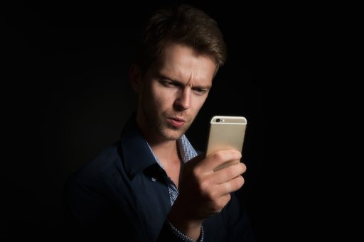 Persoon die een beleggingsapp bekijkt op zijn telefoon om een broker te kiezen voor een kleine maandelijkse inleg