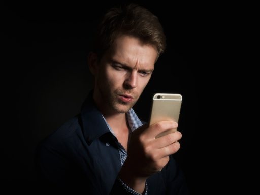 Persoon die een beleggingsapp bekijkt op zijn telefoon om een broker te kiezen voor een kleine maandelijkse inleg